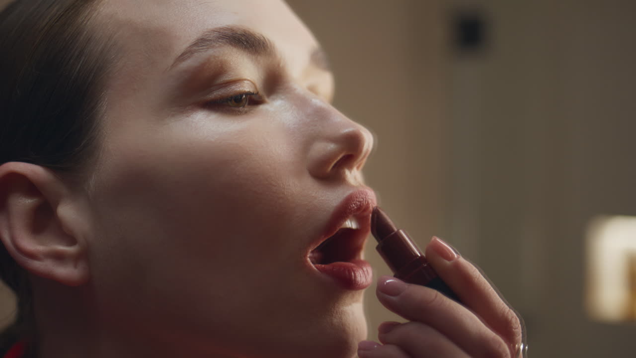 Fashion girl applying lipstick in evening light closeup. Attractive woman makeup