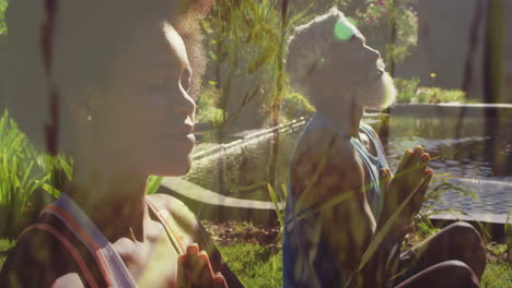 animation of grass over two diverse people practicing yoga and meditating