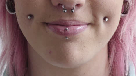 close up punk woman mouth smiling wearing piercings pink hairstyle nose ring beauty