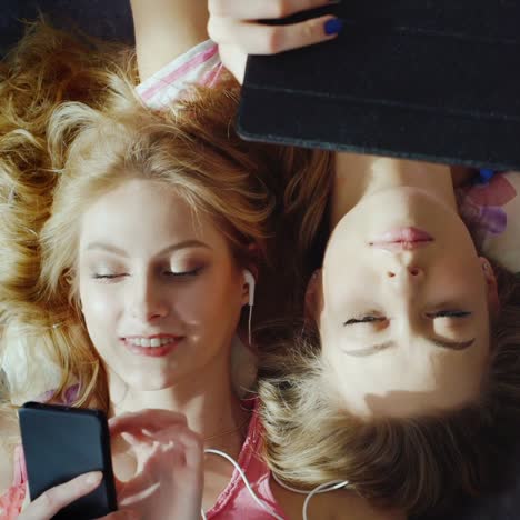 two young women relaxing at home listening to music