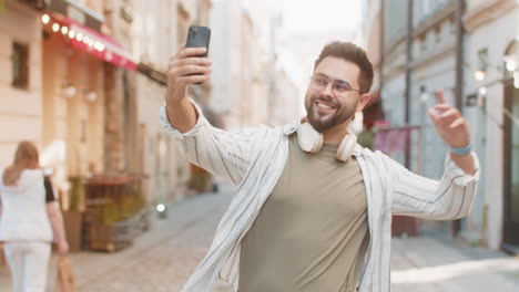 caucasian young man blogger taking selfie on smartphone having video call online on city street
