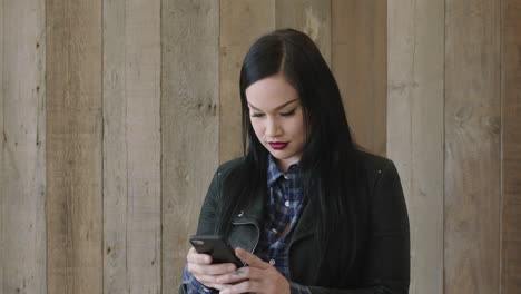 retrato de una joven y bonita mujer caucásica posando tomando una foto selfie usando tecnología de cámara de teléfono inteligente con chaqueta de cuero