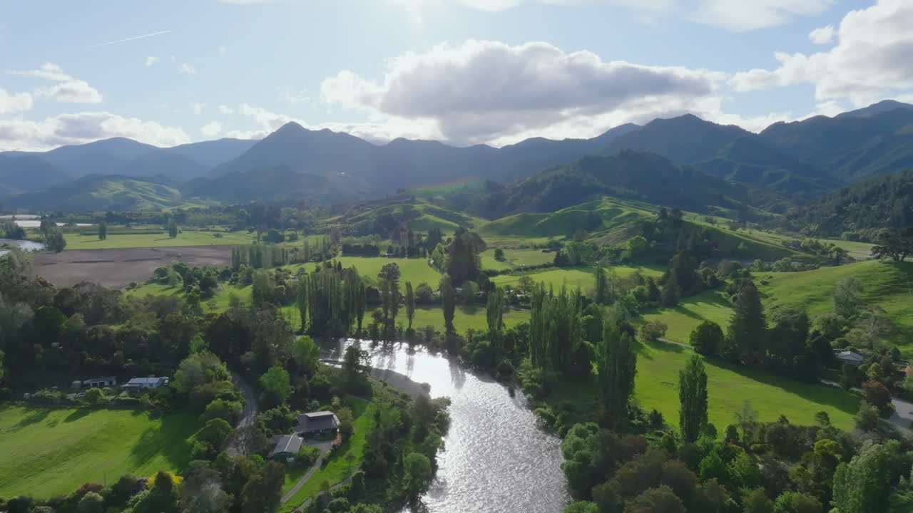 Beautiful aerial drone shot soaring over the rolling green hills and winding river in the Motueka Valley, New Zealand