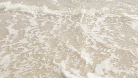 close-up of waves rolling onto tropical sand beach in slow motion