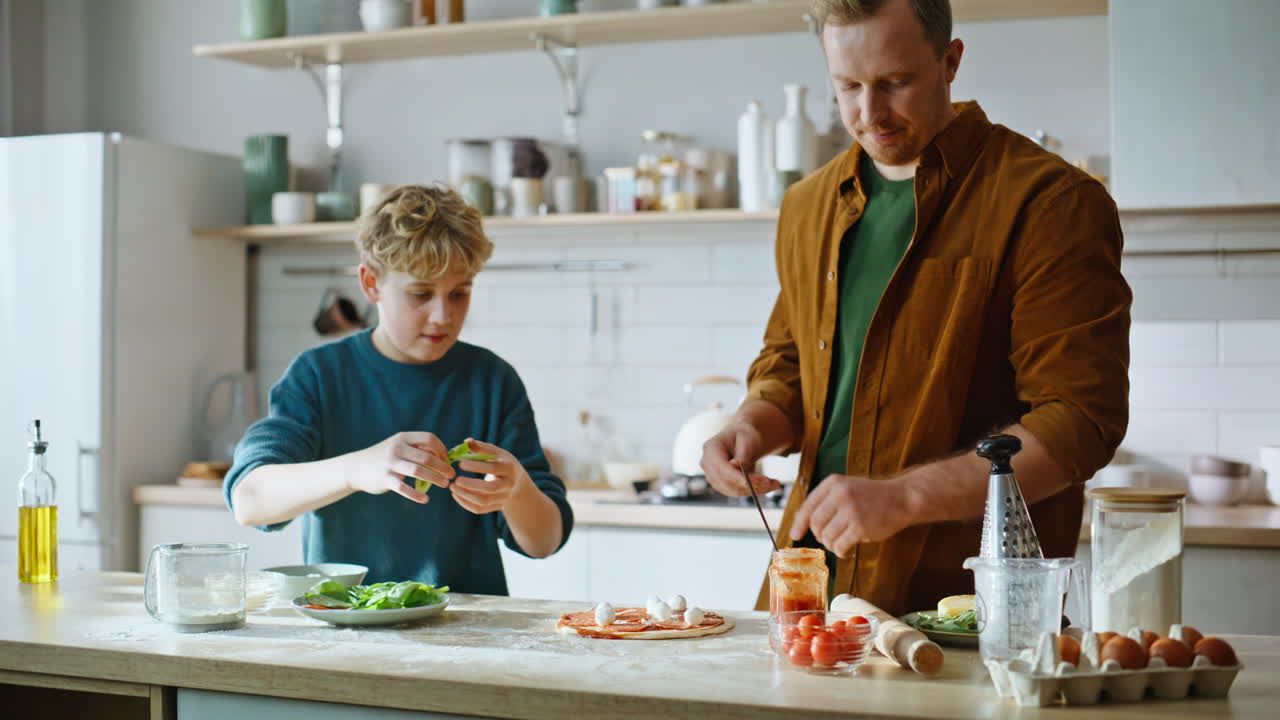 Vater und Sohn backen Pizza und belegen sie gemeinsam, Nahaufnahme in der Küche. Glücklicher Vater und Sohn.
