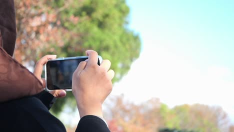 mujer tomando una foto con un teléfono inteligente en un parque