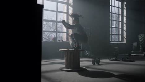 Athlete-jumping-on-wooden-box-in-gym.-Woman-doing-set-of-box-jumps-in-sport-club