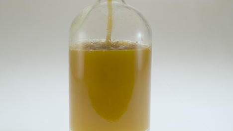 Close-up-shot-of-pouring-apple-juice-into-a-glass-bottle