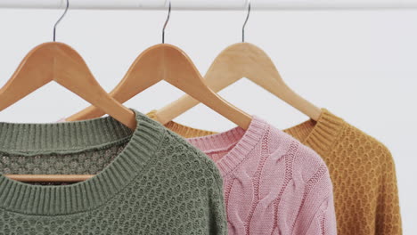video van drie veelkleurige truien op hangers en kopieerruimte op witte achtergrond