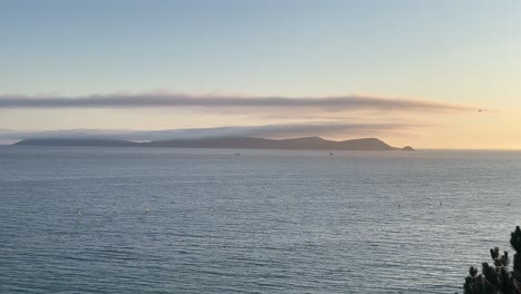 pan shot of seascape with hills at far background during sunset