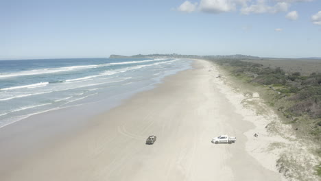 Disparo-De-Dron-De-4k-De-Ancho-De-Un-Automóvil-Turístico-Conduciendo-En-Una-Playa-Larga-Y-Caliente-En-Australia