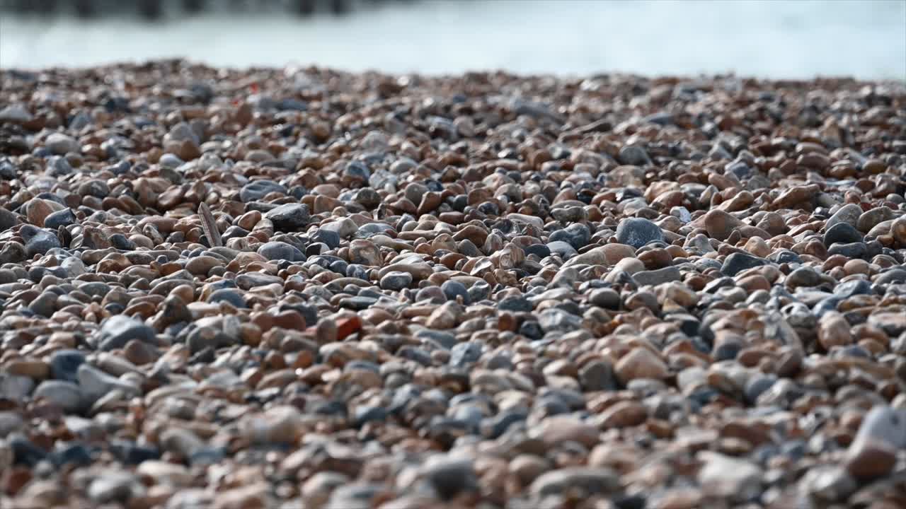 위로 기울이기: 브라이튼의 해변, 서섹스, 바닥의 자갈, 물 위의 불탄 기반 시설