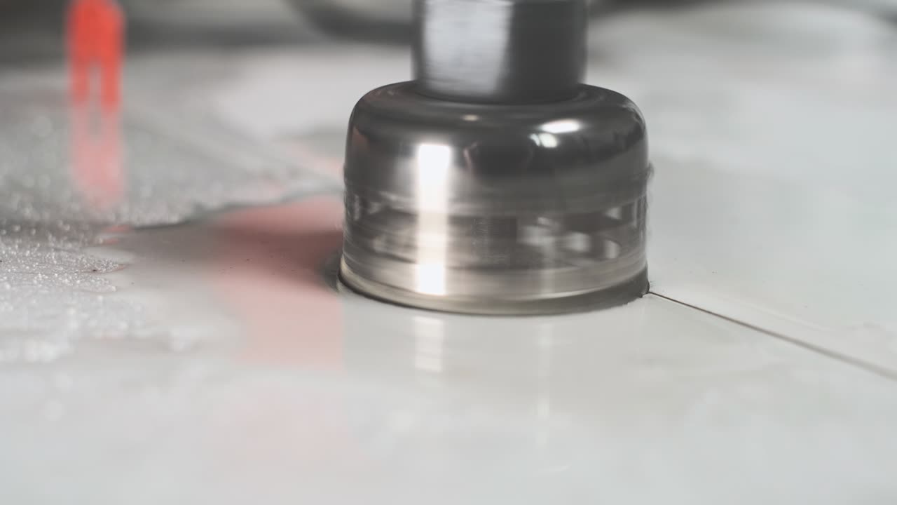 trabajador perfora cerámica de porcelana con un núcleo de diamante. perforación de mano de obra con azulejos, productos de granito o hormigón con máquina cortadora de azulejos eléctricos con corte de agua. primer plano, enfoque selectivo.