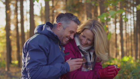 Ein-Liebendes-älteres-Paar-Macht-Auf-Einem-Spaziergang-Durch-Die-Herbst--Oder-Winterlandschaft-Pause,-Um-Sich-Auszuruhen-Und-Ein-Heißes-Getränk-Zu-Trinken-–-Aufgenommen-In-Zeitlupe