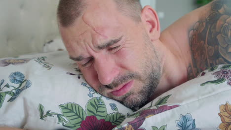 sleeping man being awakened by an alarm clock inside his bedroom