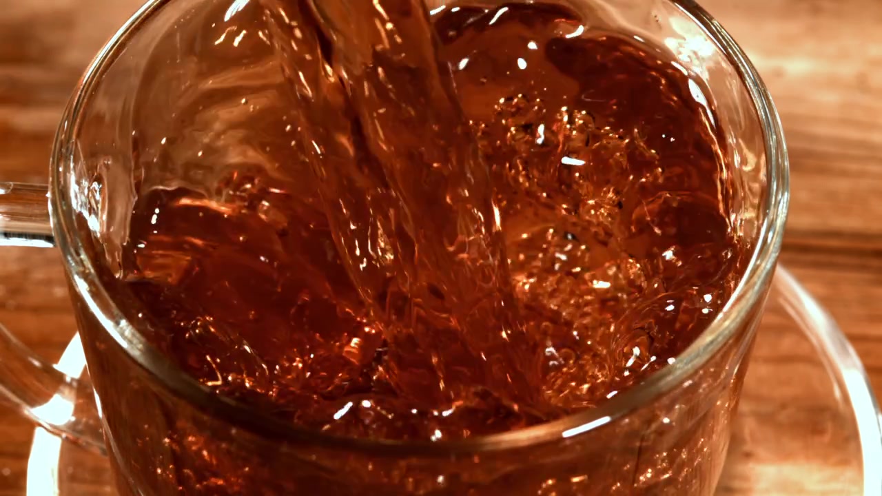 Primo piano di tè caldo versato in una tazza di vetro trasparente