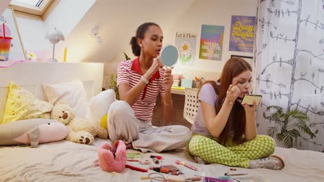 chicas adolescentes aplicando maquillaje en un dormitorio