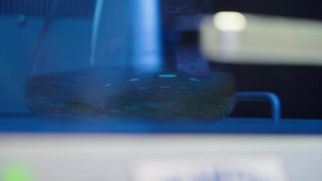 vaso de precipitados de vidrio en un agitador orbital mezclando líquido en el laboratorio de investigación científica, cierre de 4k