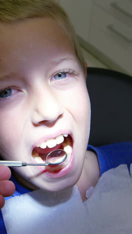 dentist examining a young patient with tools