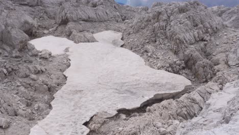 Toma-Panorámica-Hacia-Arriba-De-Una-Capa-De-Nieve-Casi-Derretida-En-Lo-Alto-De-Los-Alpes