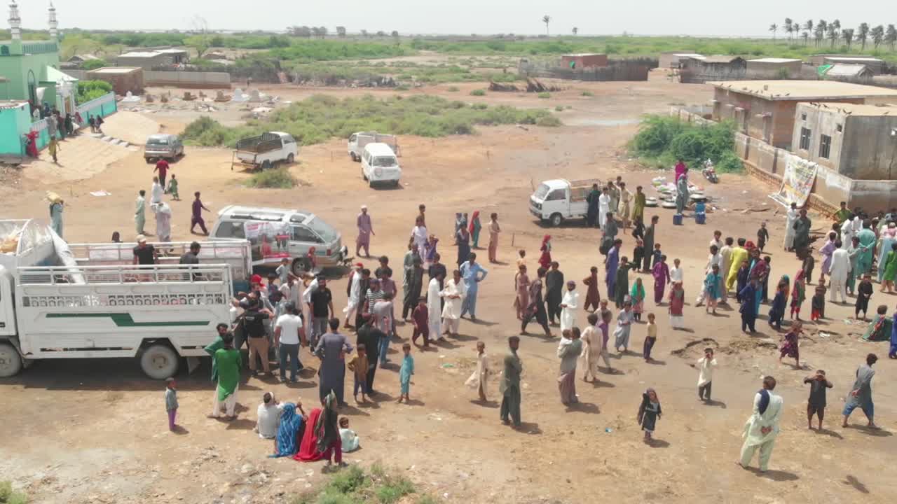 소형 트럭의 패닝 샷이 침수된 도심 도로를 탐색하여 홍수 피해자를 구하고 피해자에게 구호품을 배포합니다.