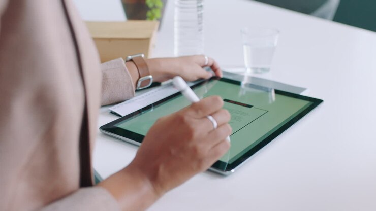 Person Using Digital Tablet with Stylus in Modern Office