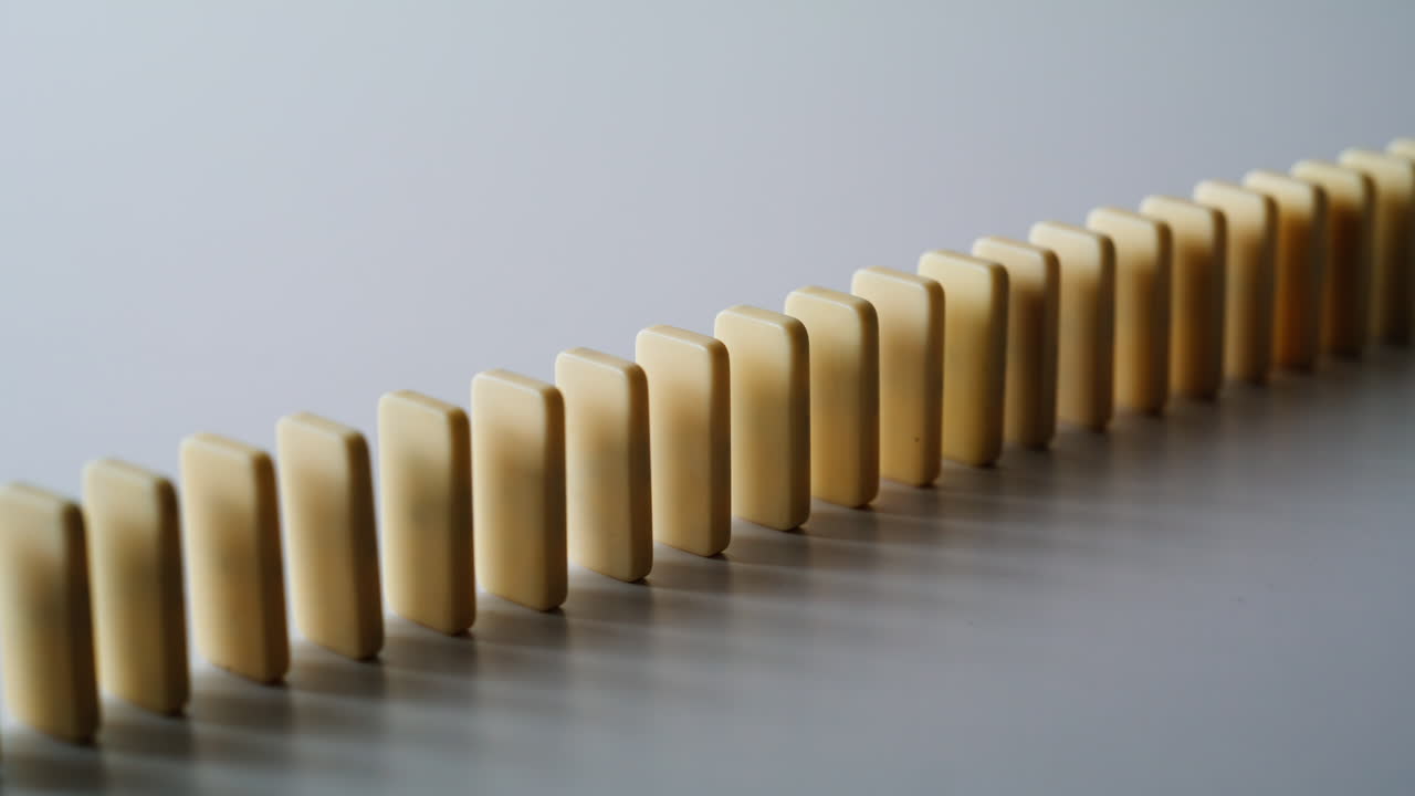 Domino line falling capture physical momentum indoors closeup. Game pieces