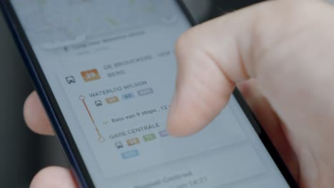 Hand-holding-and-scrolling-mobile-phone-with-mobility-planner-app-on-the-screen