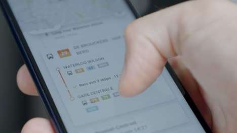 mano sujetando y desplazando el teléfono móvil con la aplicación de planificación de movilidad en la pantalla