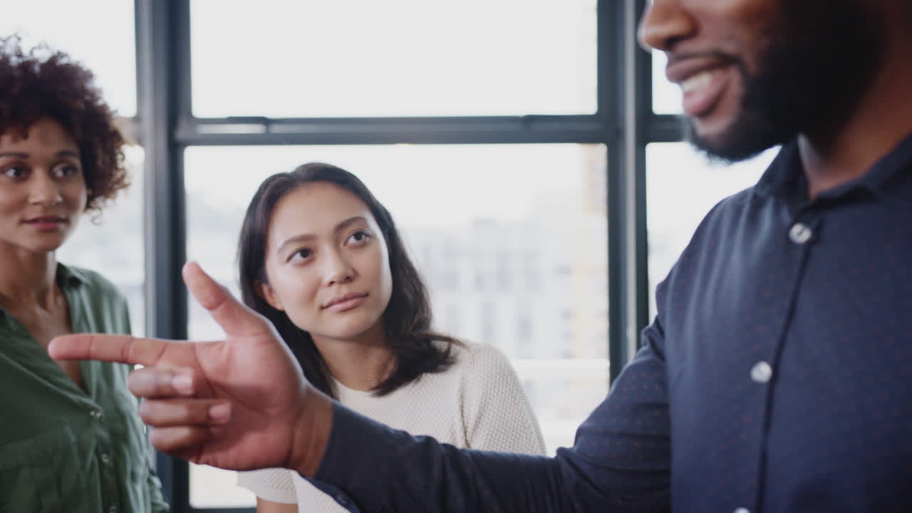 gerente dirigiéndose a colegas creativos en una reunión informal de la oficina, primer plano, tiro de arco