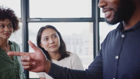 Manager-addressing-creative-colleagues-in-an-informal-office-meeting,-close-up,-arc-shot