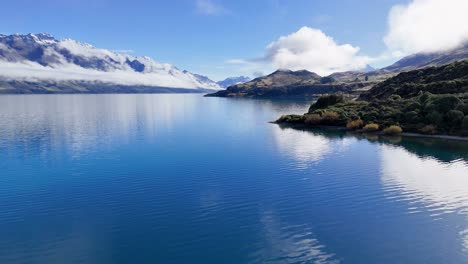 drone footage captures serene lake wakatipu with majestic mountains and clouds, showcasing new zealand's natural beauty