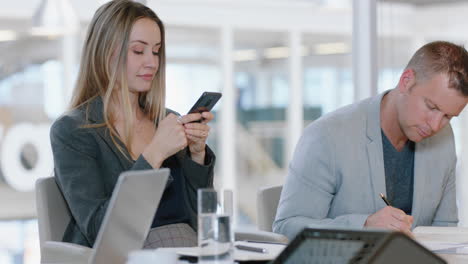 beautiful blonde business woman using smartphone in office typing messages checking emails networking with colleagues online looking bored in workplace