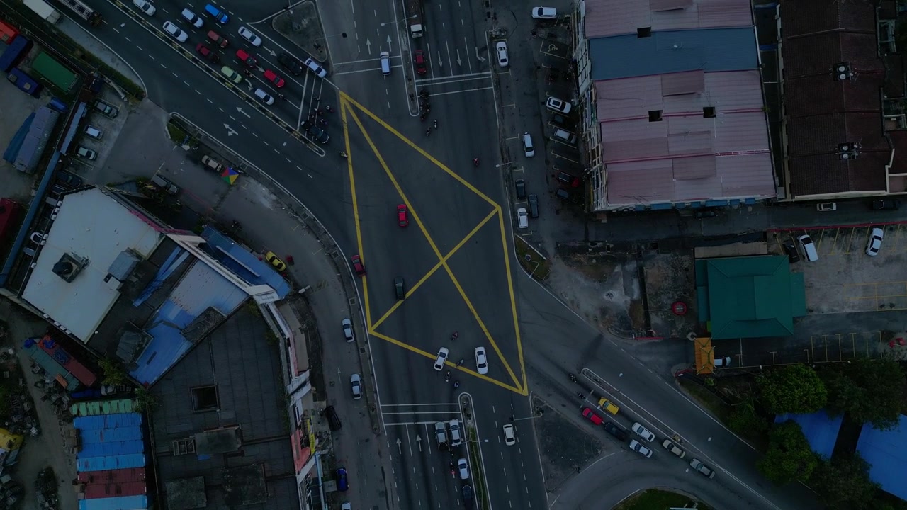 vertical bird's eye view, cars and motorbikes driving through a yellow marked box junction in Port Klang, Malaysia. Lovely aerial view drone top down Above view