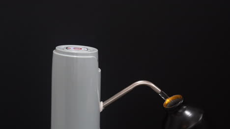 water dispenser pump wide view black background with hand filling water