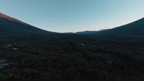 Jungle-valley-lying-in-shadow-from-massive-mountain-volcano-peak,-aerial-rotate-view