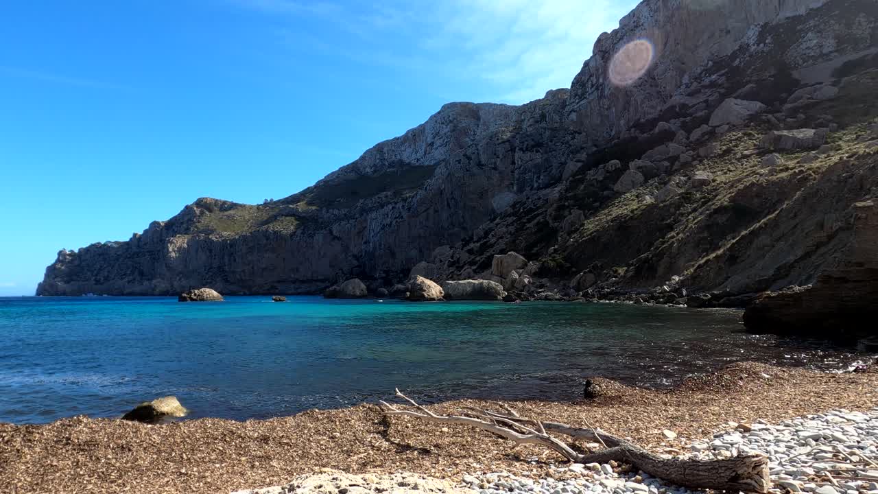 Onde calme sulla costa di Maiorca, montagne sullo sfondo, giornata di sole, nelle Isole Baleari, Spagna.