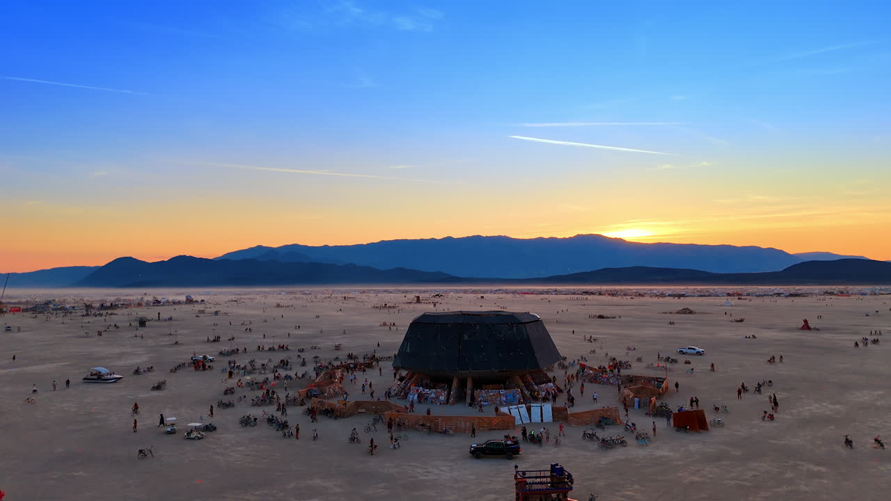 Nevada, USA, 25 August 2025: Drone aerial shot of the Burning Man temple surrounded by people and bikes in the desert at sunset