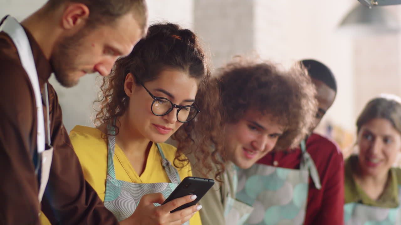 mujer filmando a un chef con un teléfono inteligente durante una clase de cocina