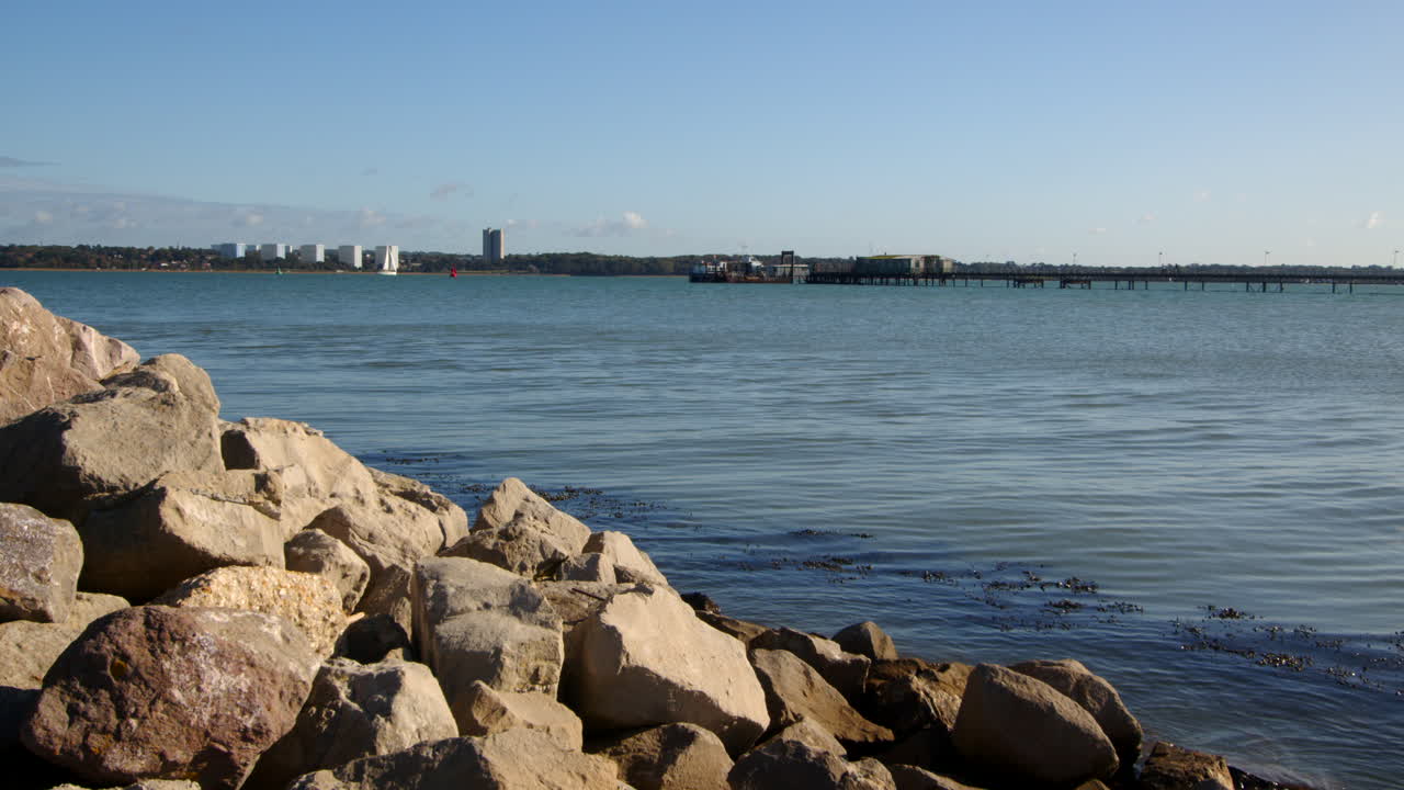 Szerokie ujęcie skał i kamieni na umocnieniach brzegowych w wiosce Hythe Marina z Weston w tle