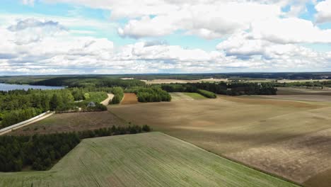 Aerial-view-of-crop-fields-and-a-lakea-in-rural-area-of-Borowy-Młyn-in-Kashubia,-Pomeranian-Voivodeship,-Poland