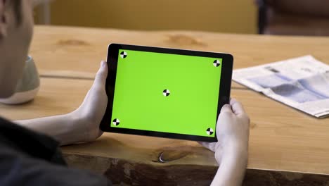 persona que sostiene una tableta con pantalla verde