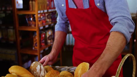 Male-staff-keeping-a-basket-of-bread-on-counter