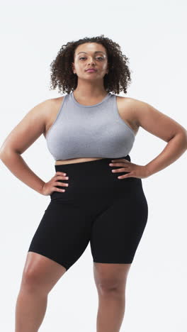 vertical video: confident plus size woman in activewear posing with hands on hips