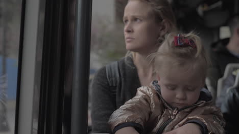 niña en el regazo de mamá en el autobús