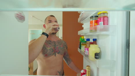 man grabbing glass of water in the fridge - close up