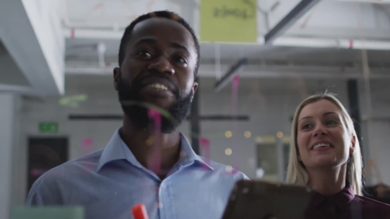 Video of four happy diverse male and female colleagues brainstorming together at night in office