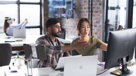 young asian man and asian woman discuss business work in a tech-filled office