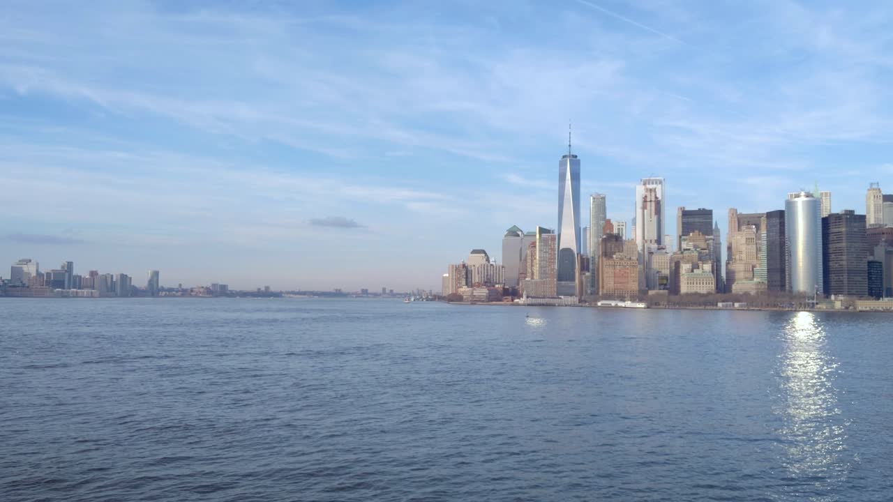 Zoom in towards the lower Manhattan waterfront skyline from the harbor in New York City