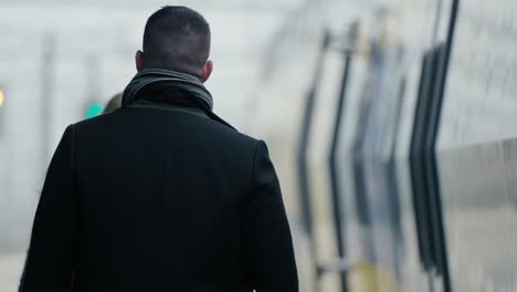 hombre mirando a la cámara y caminando con una mujer hacia la puerta abierta del tren, rotterdam